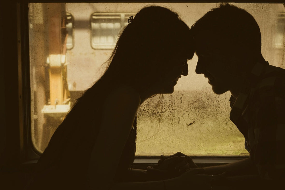 Viewed through a window, this is a silhouette of a woman and a woman touching foreheads, demonstrating emotional intimacy
