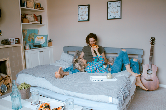 Couple eating pizza together on the bed