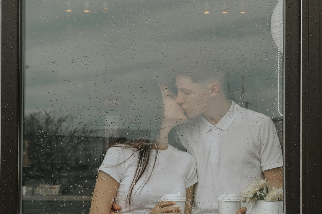 Couple looking out of the window together on a rainy day