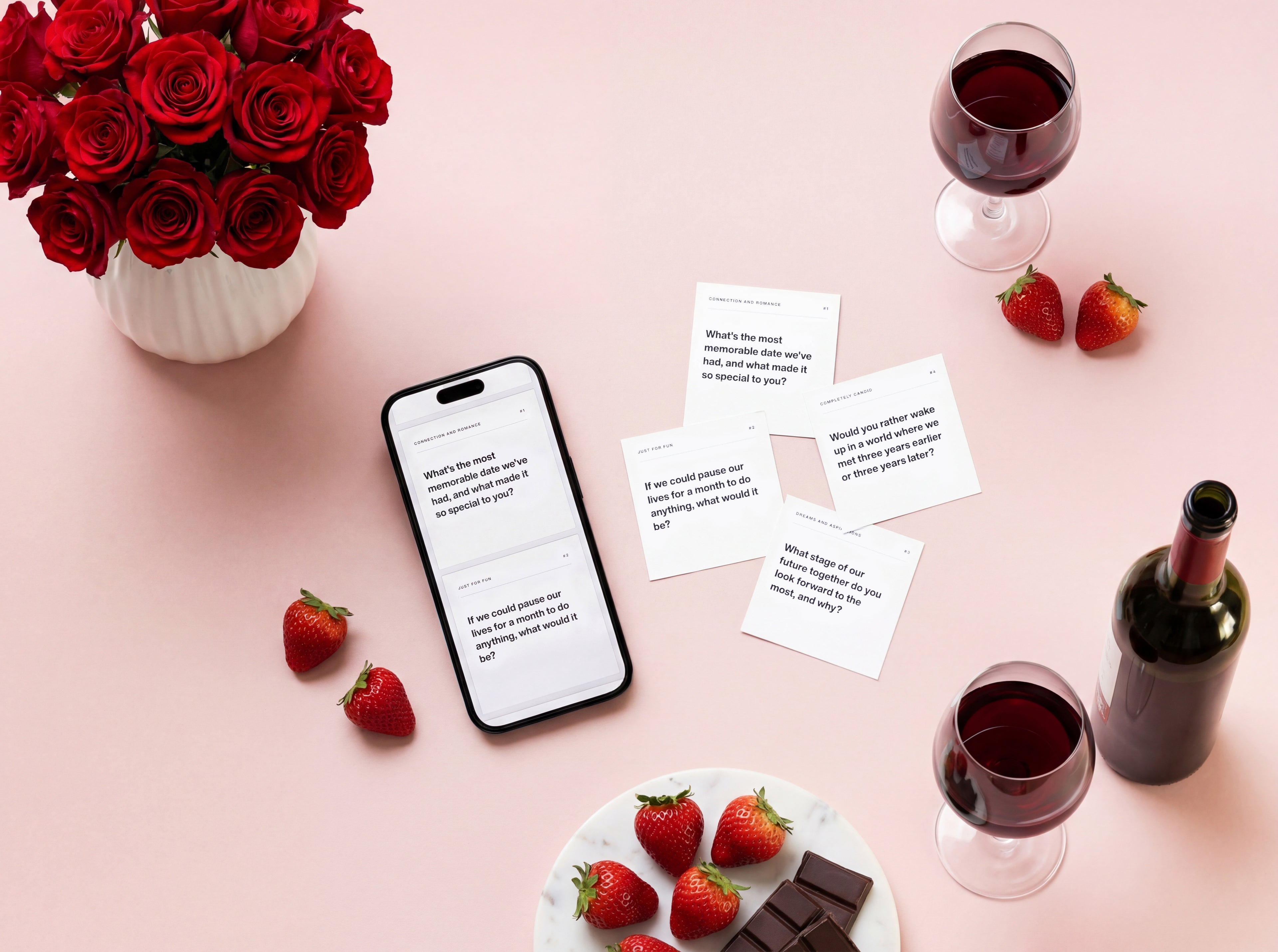 Printed couples edition cards and a smartphone with digital cards on a table with flowers, strawberries, chocolate, and wine